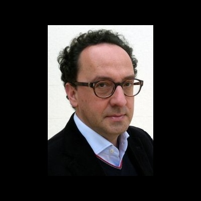 Homem com óculos de armação castanha e roupa formal contra fundo branco