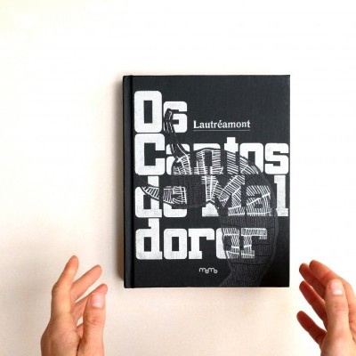 Livro 'Os Cantos de Maldoror' de capa preta com texto branco e mãos segurando-o.