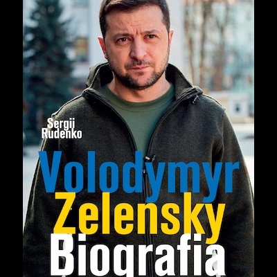 Capa do livro 'Volodymyr Zelensky Biografia' com foto de homem em casaco verde em fundo urbano desfocado