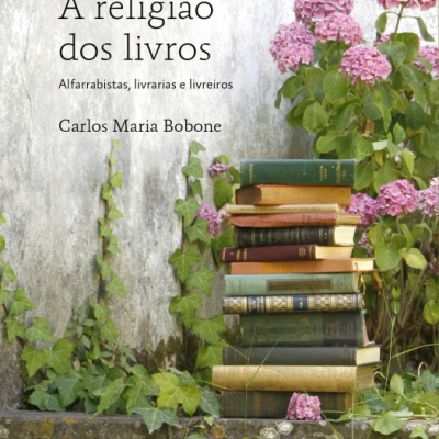 Capa do livro A religião dos livros com pilha de livros antigos e flores cor-de-rosa