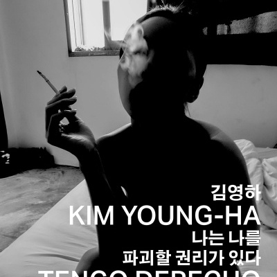 Pessoa sentada numa cama a fumar com texto em coreano e espanhol sobreposto