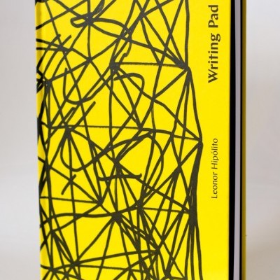 Bloco de notas amarelo com linhas pretas e texto Writing Pad Leonor Hipólito