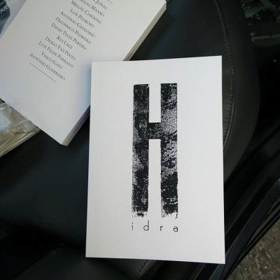 Dois livros em capa branca com texto em preto, um com grande H e 'idra', outro aberto com lista de nomes