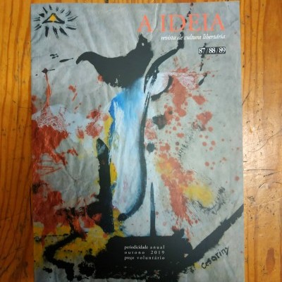 Revista A IDEIA com capa abstrata colorida sobre chão de madeira
