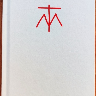 Livro com capa branca e símbolo vermelho no centro