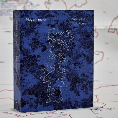 Livro azul com mapa desenhado sobre fundo com mapa impresso