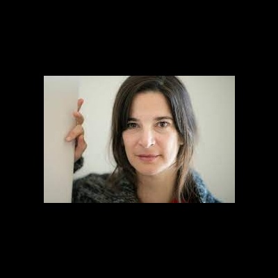 Mulher com cabelo castanho a usar camisola cinzenta junto a parede branca