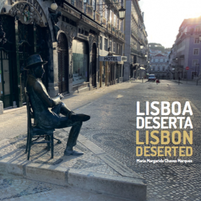 Estátua de bronze de homem sentado na calçada em rua deserta de Lisboa com texto LISBOA DESERTA LISBON DESERTED