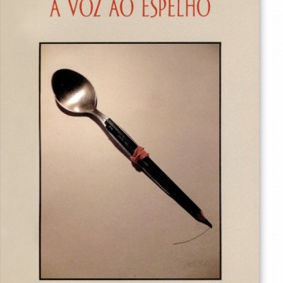Capa de livro com título A VOZ AO ESPELHO e imagem de colher presa a objeto preto