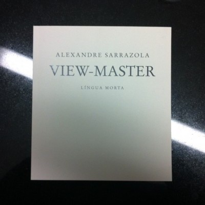 Capa branca de álbum ou livro com texto preto sobre superfície escura