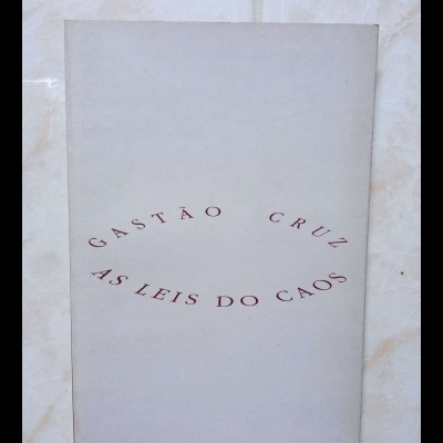 Livro cinzento com texto vermelho 'GASTÃO CRUZ AS LEIS DO CAOS' contra parede de azulejos.