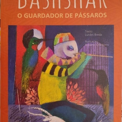Capa de livro colorida com figura humana e pássaros, texto visível no livro.