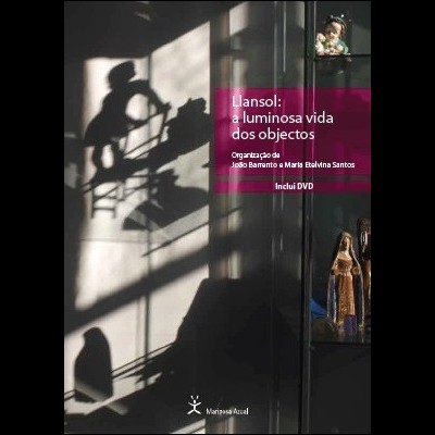 Capa de livro com sombras e objetos numa estante de vidro