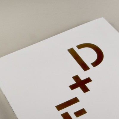 Pacote branco com caracteres dourados 'D+' em relevo