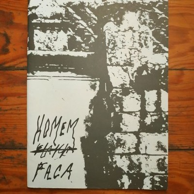 Capa de livro ou revista preto e branco com texto manuscrito e imagem de paredes de pedra