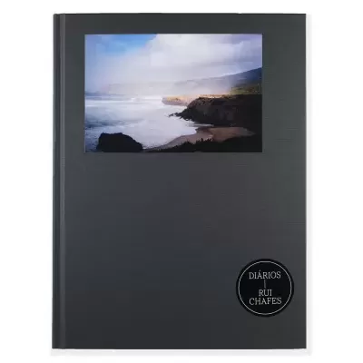 Caderno preto com foto de paisagem costeira e selo preto com texto branco
