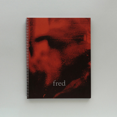 Caderno espiral com capa vermelha e preta com a palavra fred.