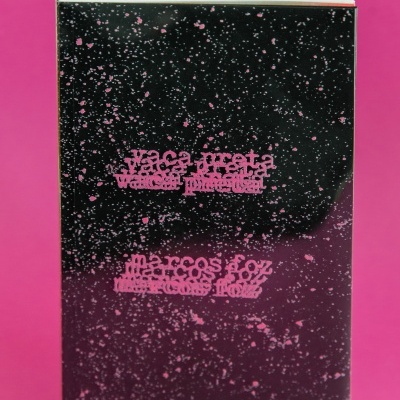 Livro com capa preta e salpicos rosa com texto em rosa sobre fundo rosa.