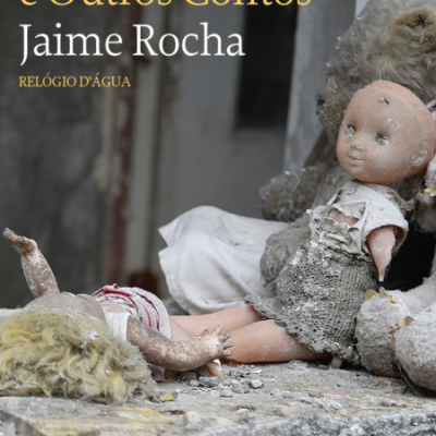 Capa de livro com título e duas bonecas antigas sujas sobre pedra em fundo desfocado