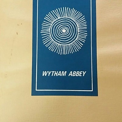 Capa de livro com texto e desenho branco em fundo azul, em cima de mesa clara