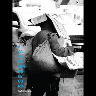 Pessoa com caixas de cartão e sacola, em ambiente urbano com carros ao fundo