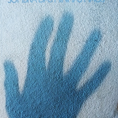 Capa de livro com sombra azul de uma mão sobre fundo branco texturizado e texto ANTÓNIO BARONNA SOMBRA DAS MINHAS MÃOS