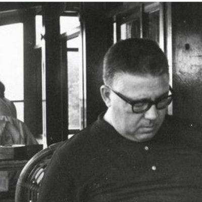 Capa de livro com título vermelho, autor e foto a preto e branco de homem sentado a ler.