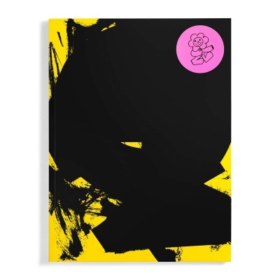 Capa de livro amarelo com pintura negra e autocolante rosa com flor a segurar caneta