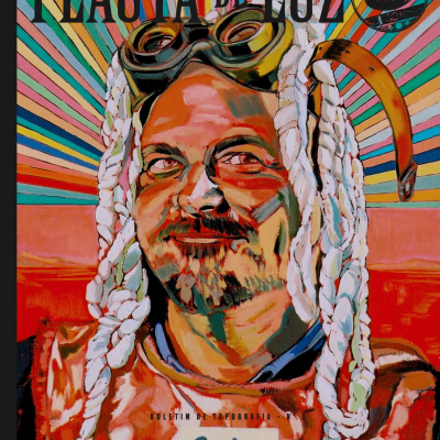 Capa de revista com retrato colorido de homem com óculos, roupa vermelha e cabelo trançado em fundo colorido.