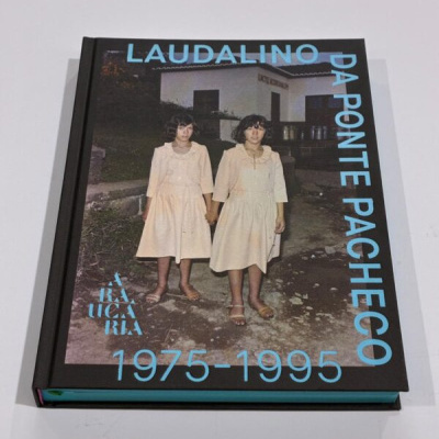 Capa de livro preto com fotografia de duas meninas de vestido creme e texto azul