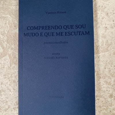 Livro azul escuro com texto no centro sobre superfície cinza clara texturada