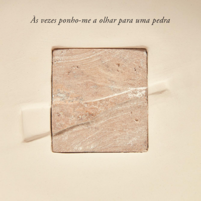 Placa quadrada de pedra castanha com texto em português num fundo bege