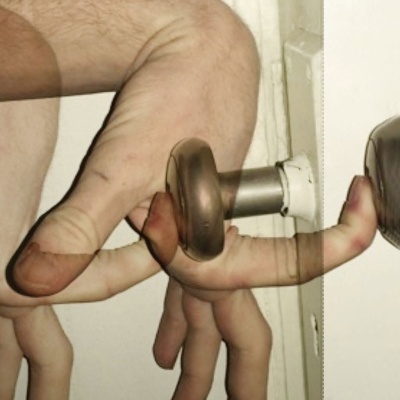 Mão humana segurando puxador metálico redondo de porta com texto RESIGNAÇÃO INFINITA EUGENE THACKER.