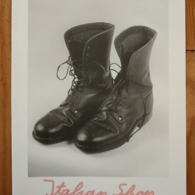 Par de botas de couro pretas com atacadores pretos em foto a preto e branco, título 'Fernando Guerreiro', texto 'Italian Shoes' em vermelho