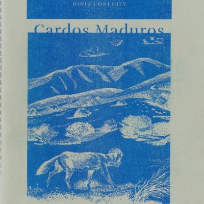 Livro com capa cinzenta, ilustração azul de montanhas e cão, texto DINIZ CONEFREY e Cardos Maduros.