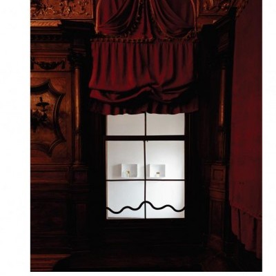 Janela clássica com cortinas vermelhas e objetos claros em fundo branco iluminado