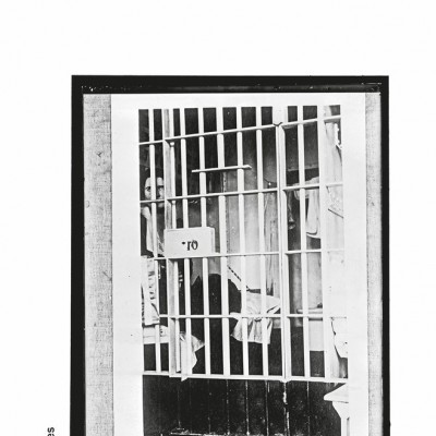 Capa do livro 'Entretanto' de John Berger com fotografia em preto e branco de pessoas atrás de grades.