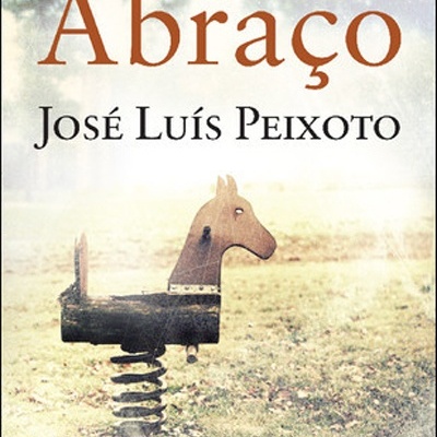 Capa de livro com título 'Abraço' e autor 'José Luís Peixoto', com brinquedo de parque em forma de cavalo