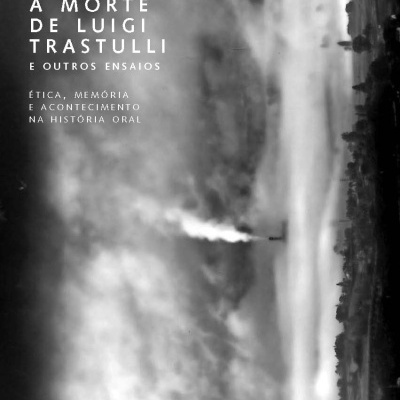 Capa do livro A Morte de Luigi Trastulli e Outros Ensaios com texto branco sobre fundo preto e branco de paisagem e chaminé a emitir fumo