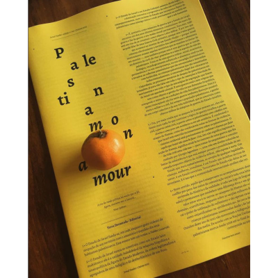 Página amarela com texto em português e tangerina sobre mesa de madeira