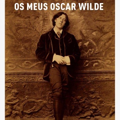 Capa do livro 'Os Meus Oscar Wilde' de André Gide com imagem em sépia de homem jovem com fato formal encostado a muro decorado