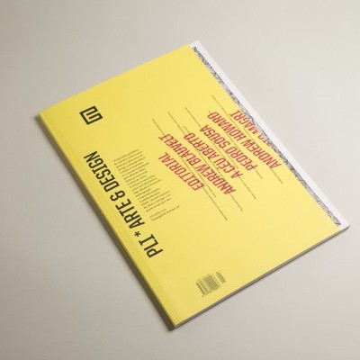 Caderno amarelo com texto PL + ARTE E DESIGN sobre superfície cinza