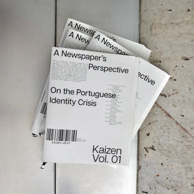 Revistas brancas com texto impresso sobre identidade portuguesa, sobre superfície metálica prateada e piso de cimento