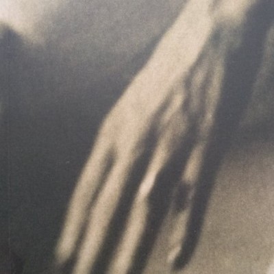 Mão desfocada em preto e branco com dedos longos.