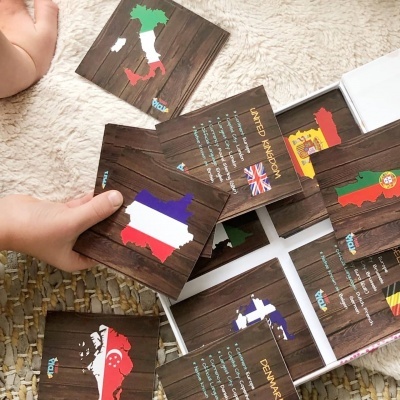 Cartas educativas com mapas coloridos de países e bandeiras em fundo de madeira.