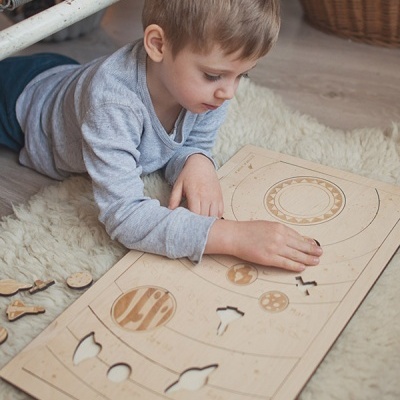 Criança a brincar com painel educativo de madeira no chão felpudo