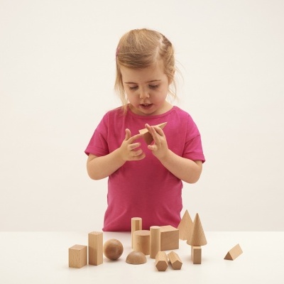 Menina a brincar com blocos de madeira de formas geométricas