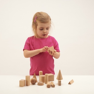 Criança a brincar com blocos de madeira numa mesa branca.