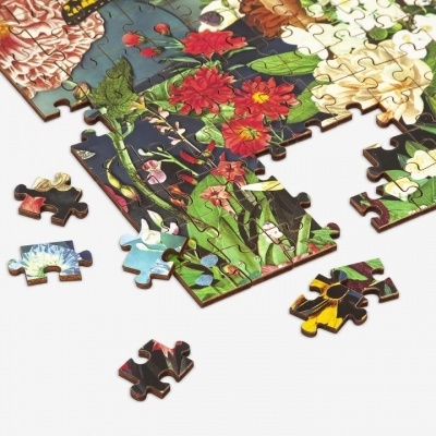 Peças de puzzle de madeira com flores coloridas, parcialmente montado sobre fundo branco.