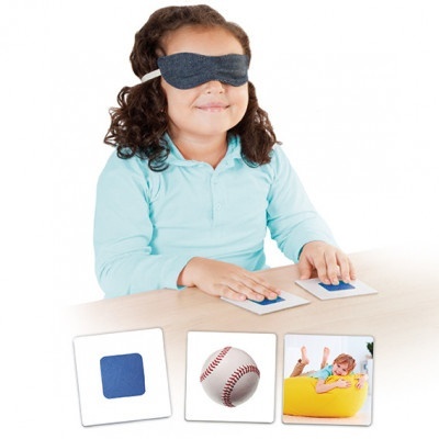 Criança com máscara cinzenta a tocar cartões na mesa com imagens diversas